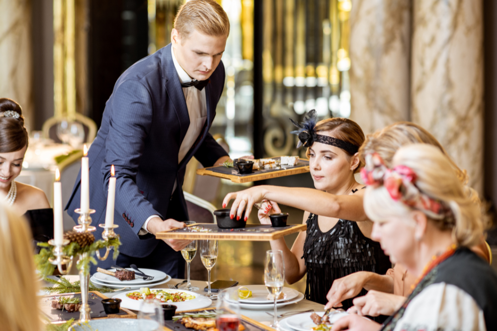 Waiter serving guests at a formal reception, illustrating what does all inclusive mean in an indoor venue with full-service catering.